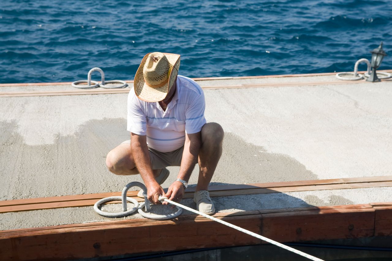 A marina operator tying a boat’s line to the dock